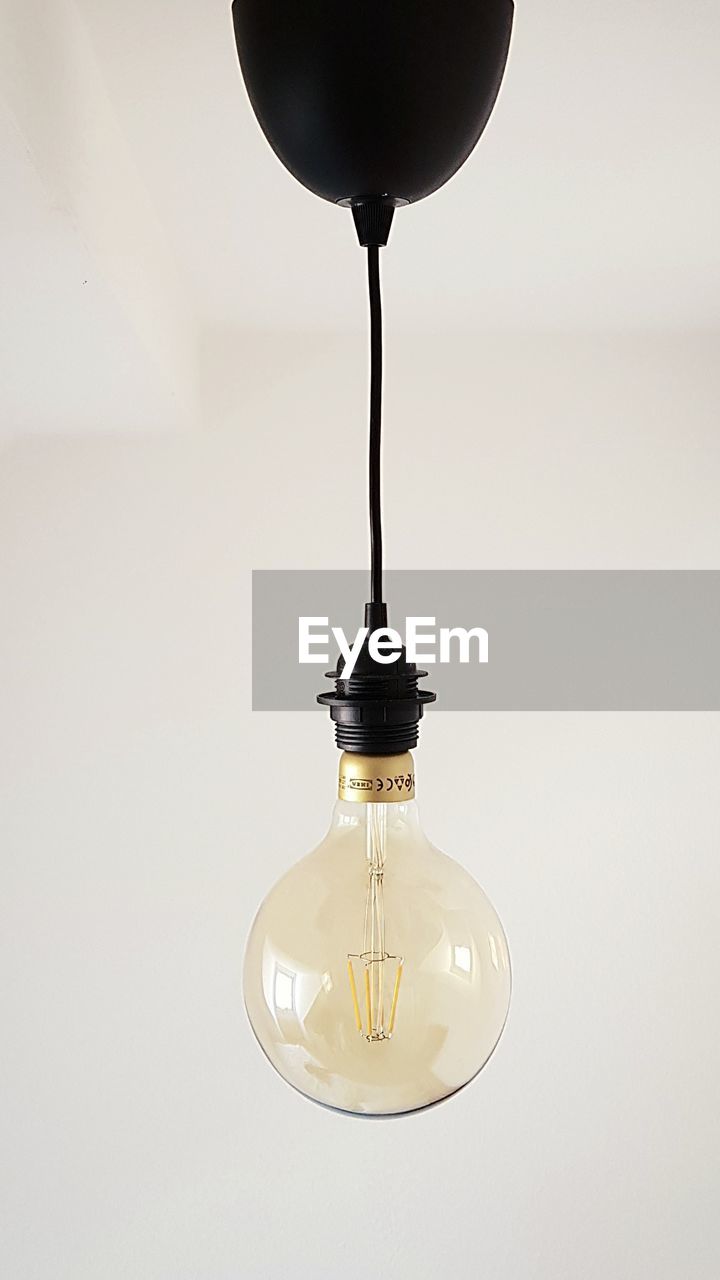 CLOSE-UP OF LIGHT BULB AGAINST WALL