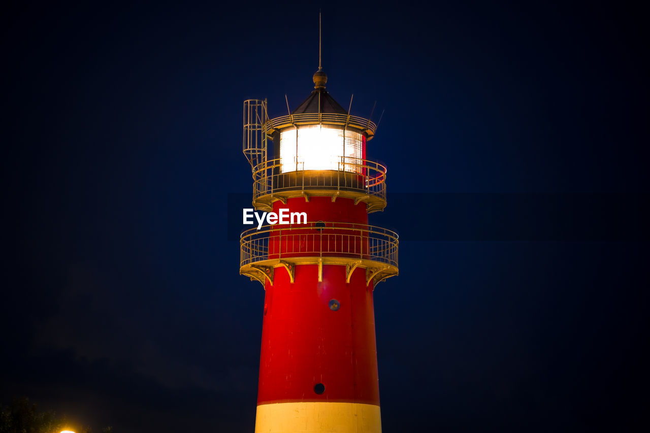 Low angle view of illuminated lighthouse against sky at night in büsum 