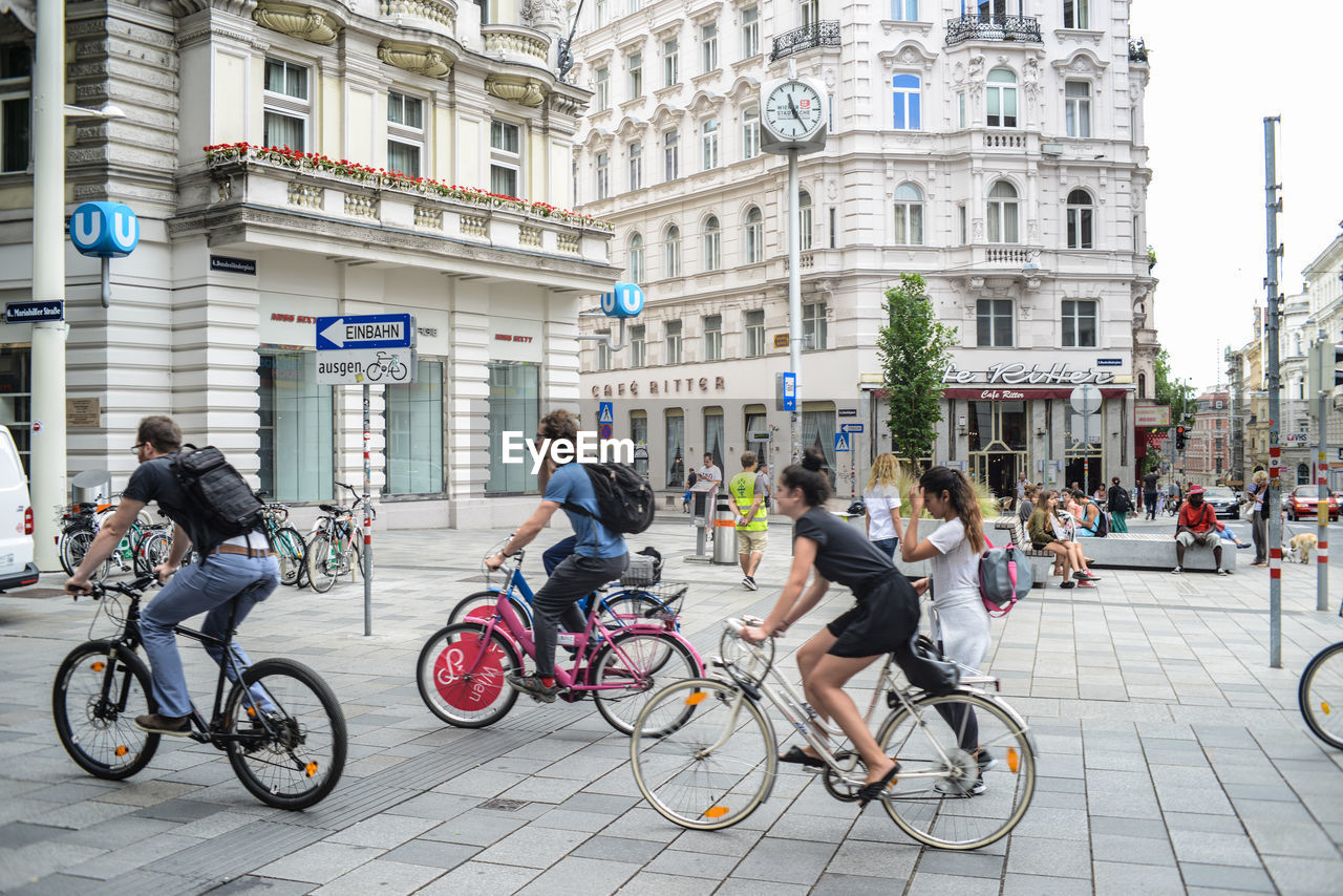 People riding bicycle on street against buildings