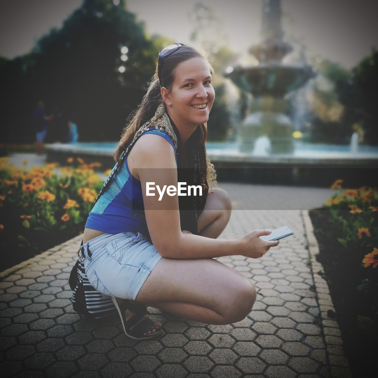 PORTRAIT OF A SMILING YOUNG WOMAN SITTING ON FLOOR