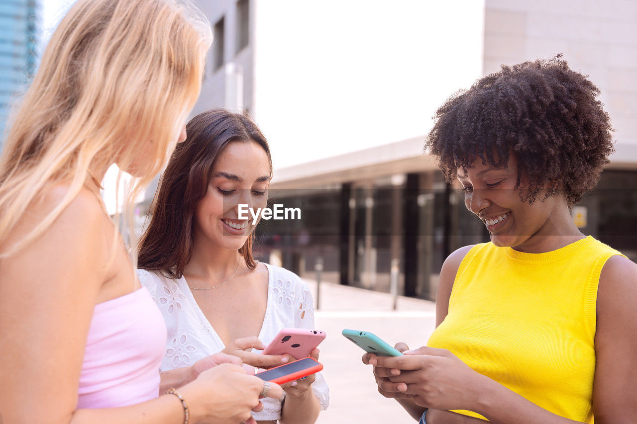 side view of young friends using mobile phone
