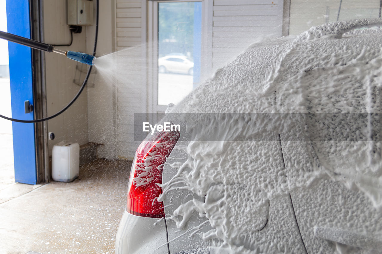 Soap detergent foam application process while washing indoors at self-service carwash station