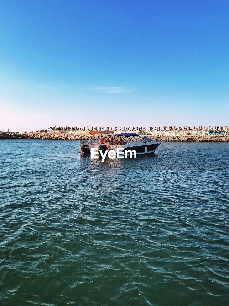 People on sea against clear blue sky