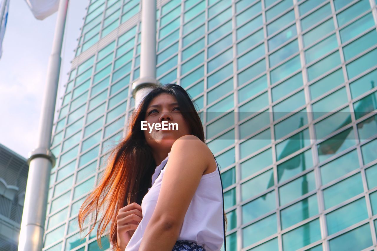 Low angle view of young woman standing in front of building