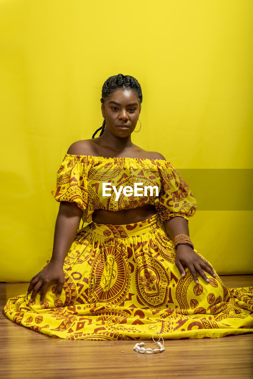 Young woman wearing colorful long clothes over yellow background. natural expression.