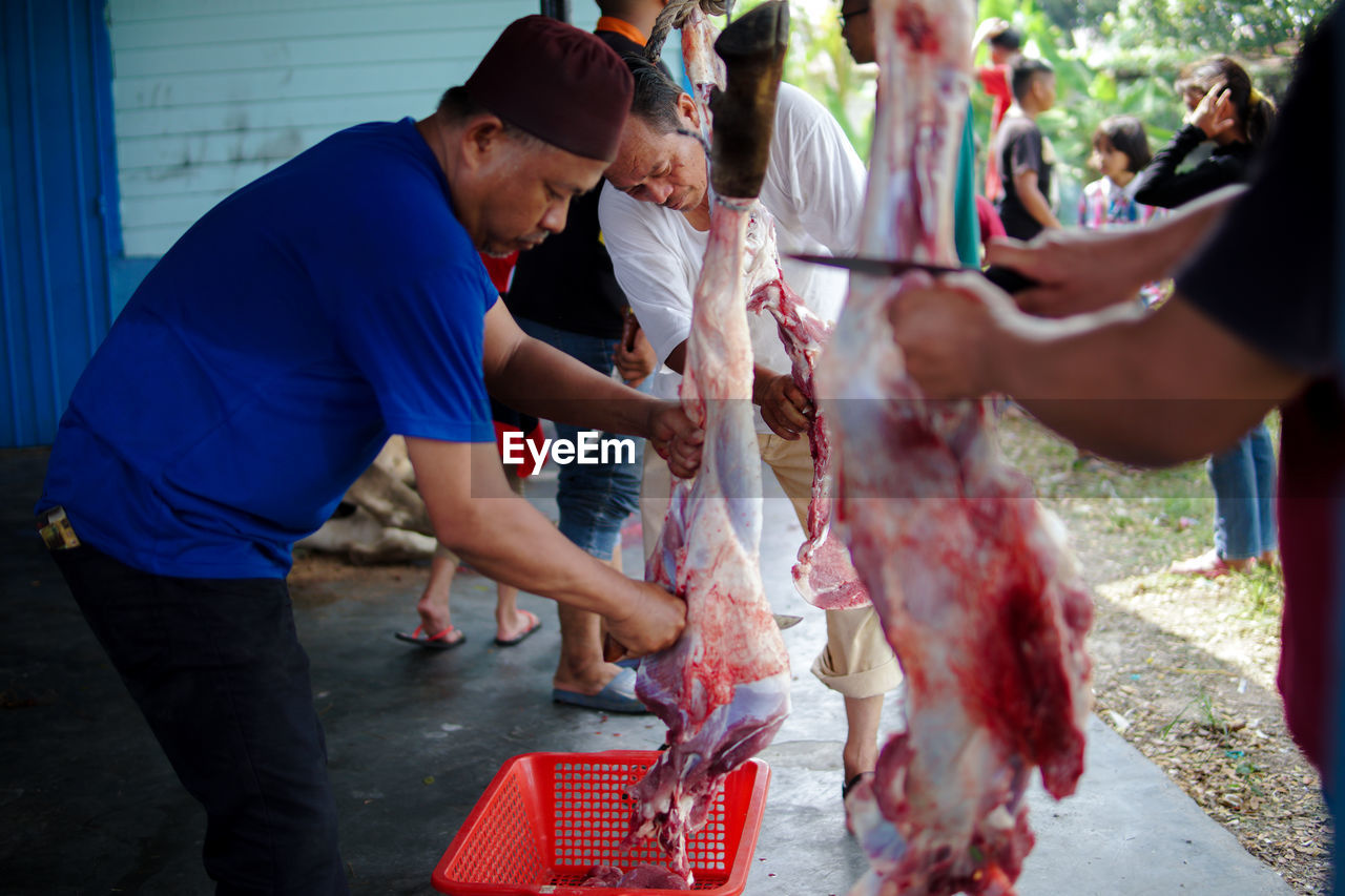 REAR VIEW OF PEOPLE STANDING BY FOOD