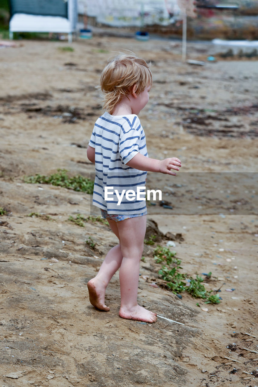 full length of boy running on sand at beach