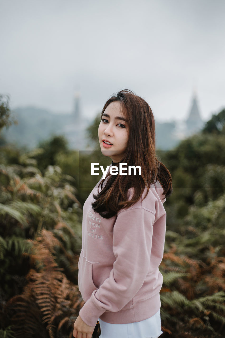 Portrait of beautiful young woman standing on land