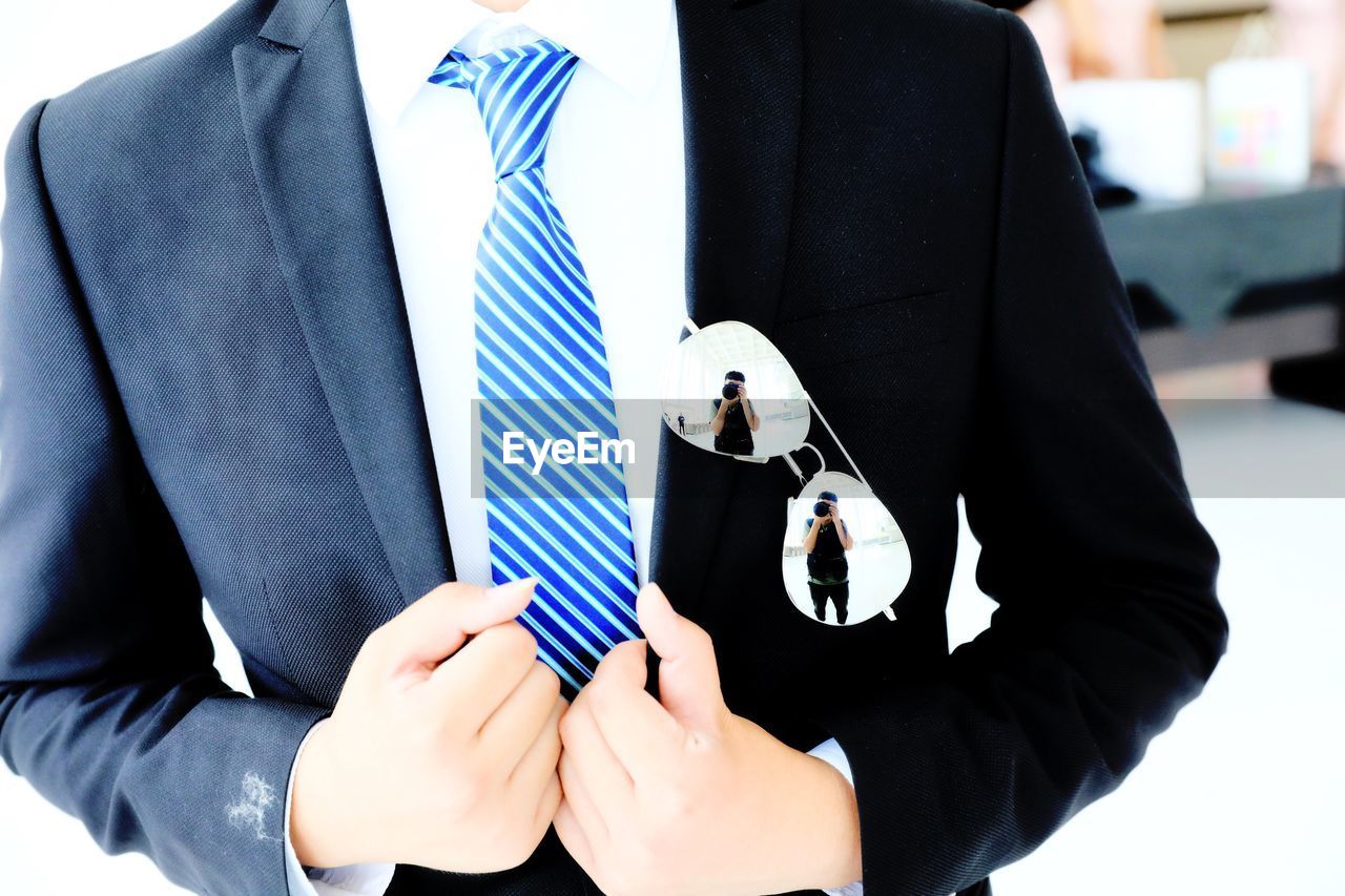 MIDSECTION OF MAN HOLDING CAMERA