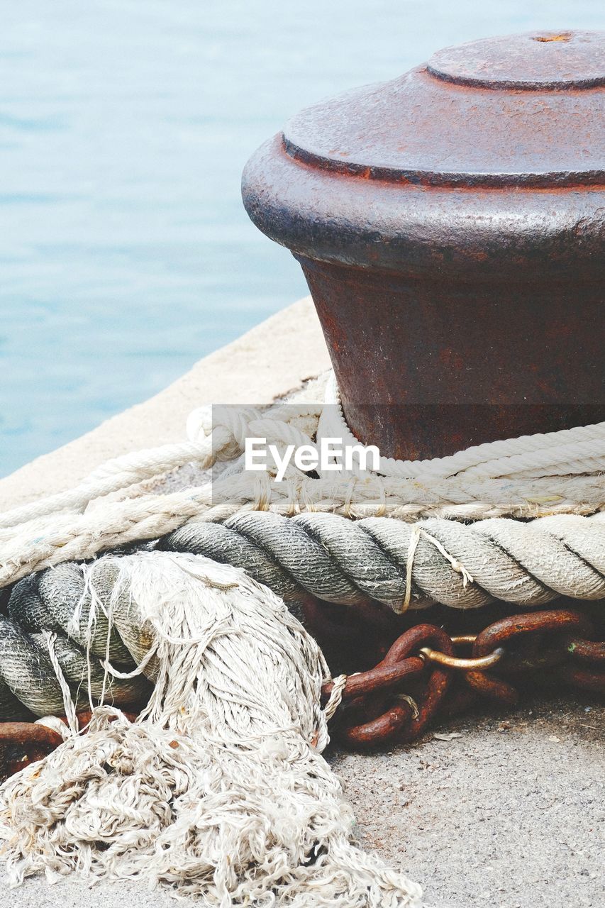 CLOSE-UP OF ROPE TIED TO BOLLARD