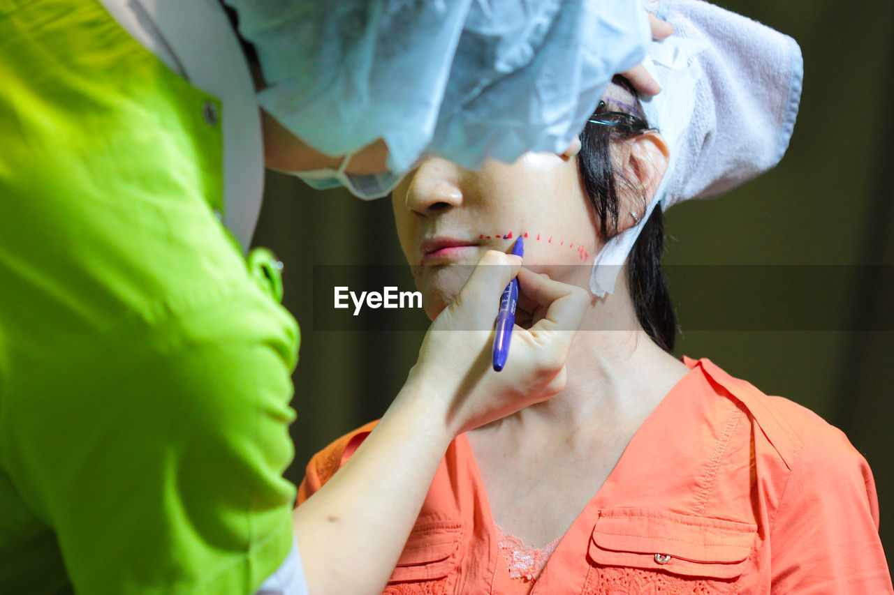 Doctor making markings on patient face in operating room