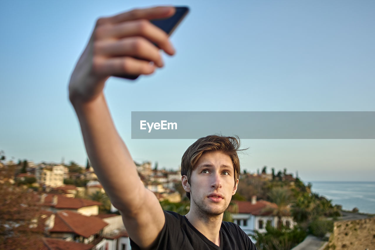 Portrait of man using smart phone against sky