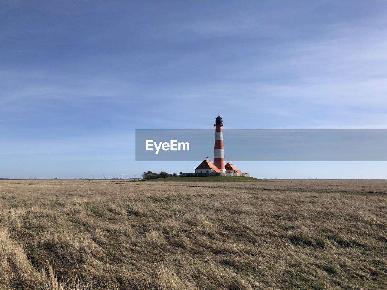 Lighthouse on field against sky