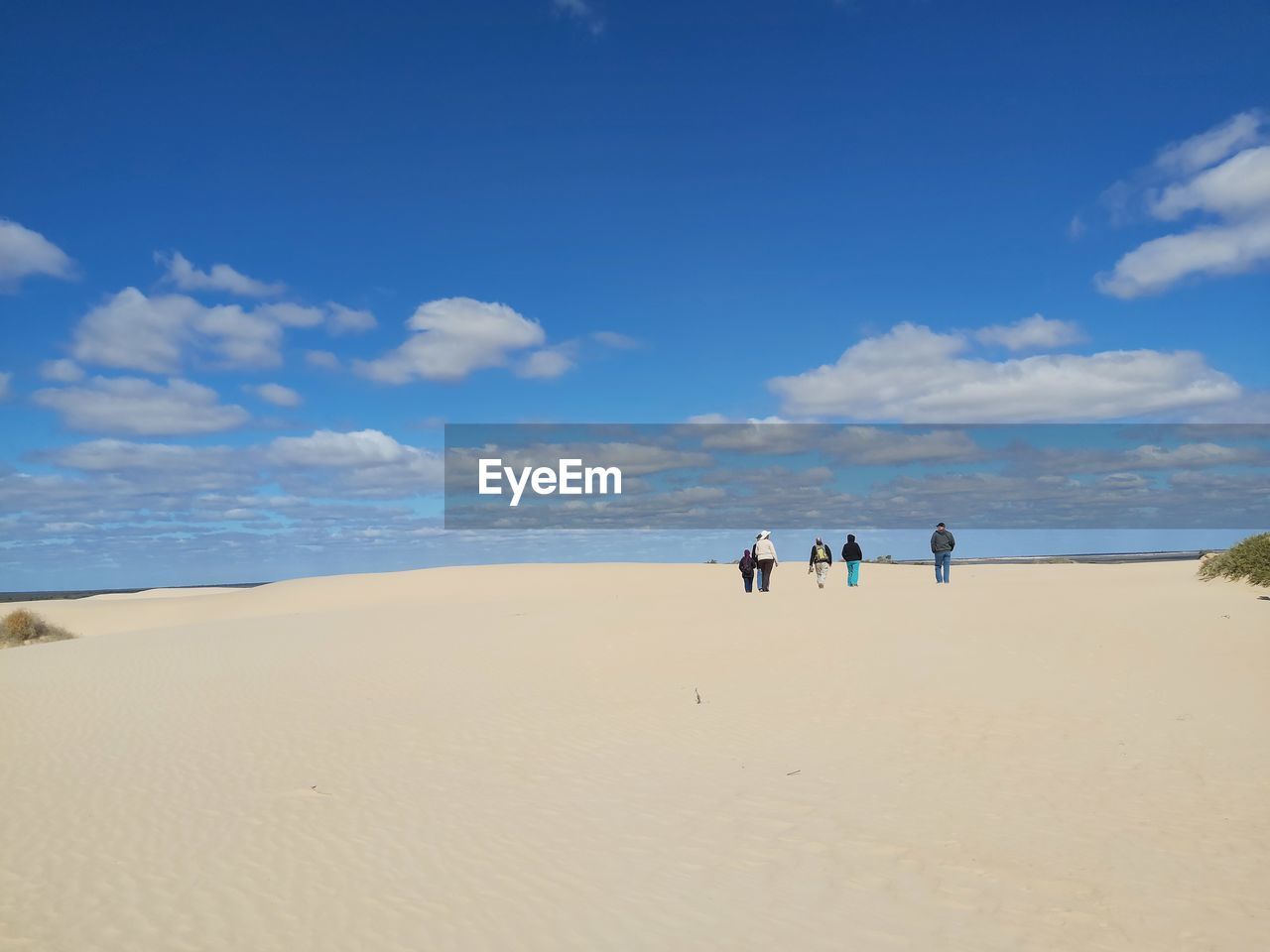 PEOPLE AT BEACH AGAINST BLUE SKY