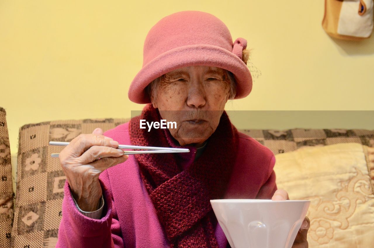 Portrait of senior woman eating food at home