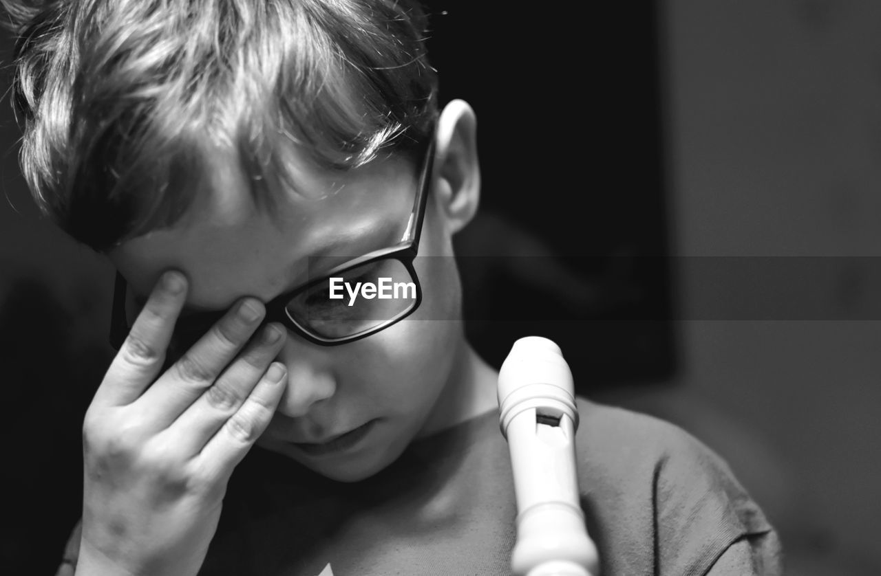Close-up of tired boy wearing eyeglasses at home