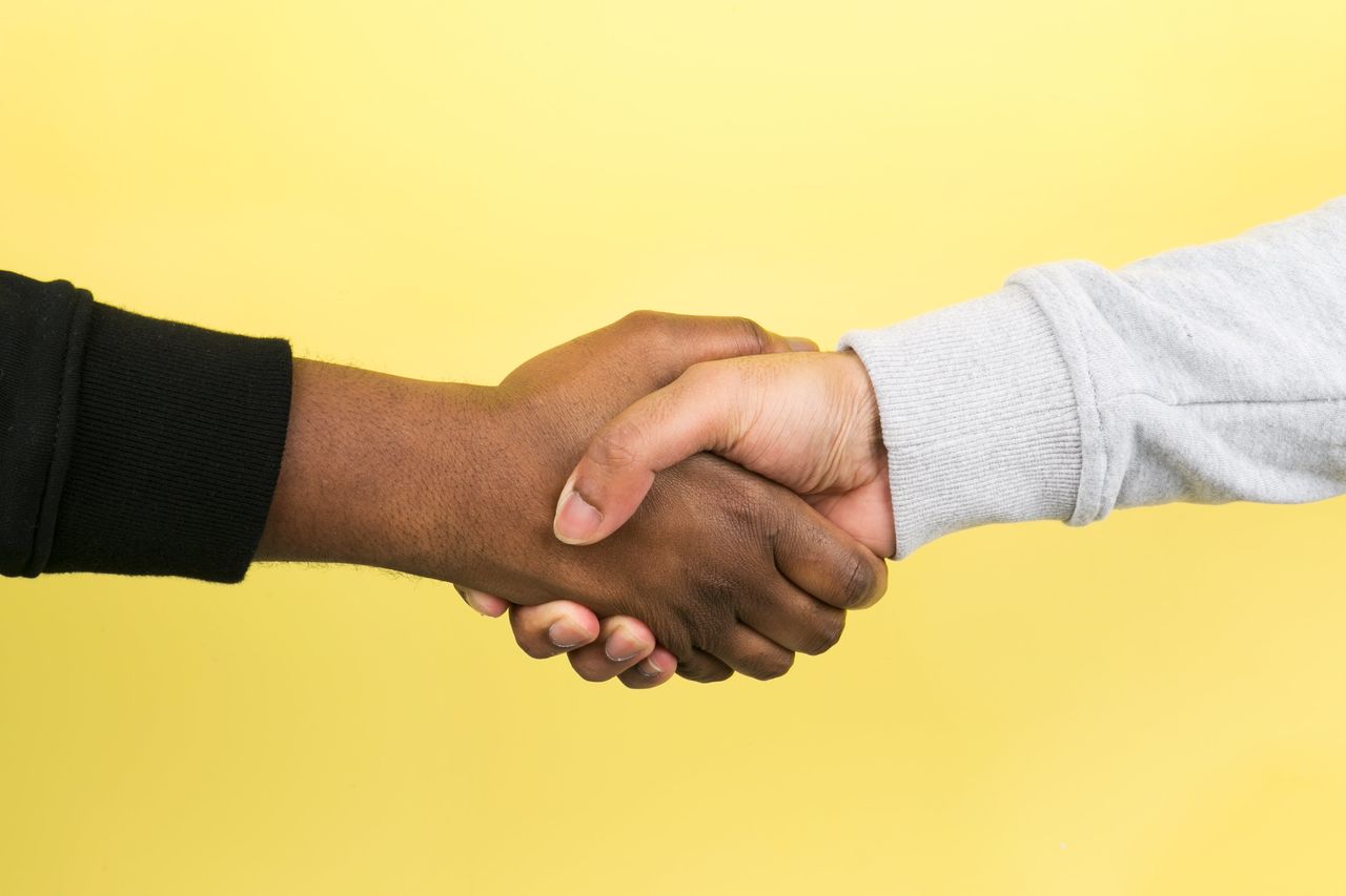 Cropped image of couple holding hands against yellow background