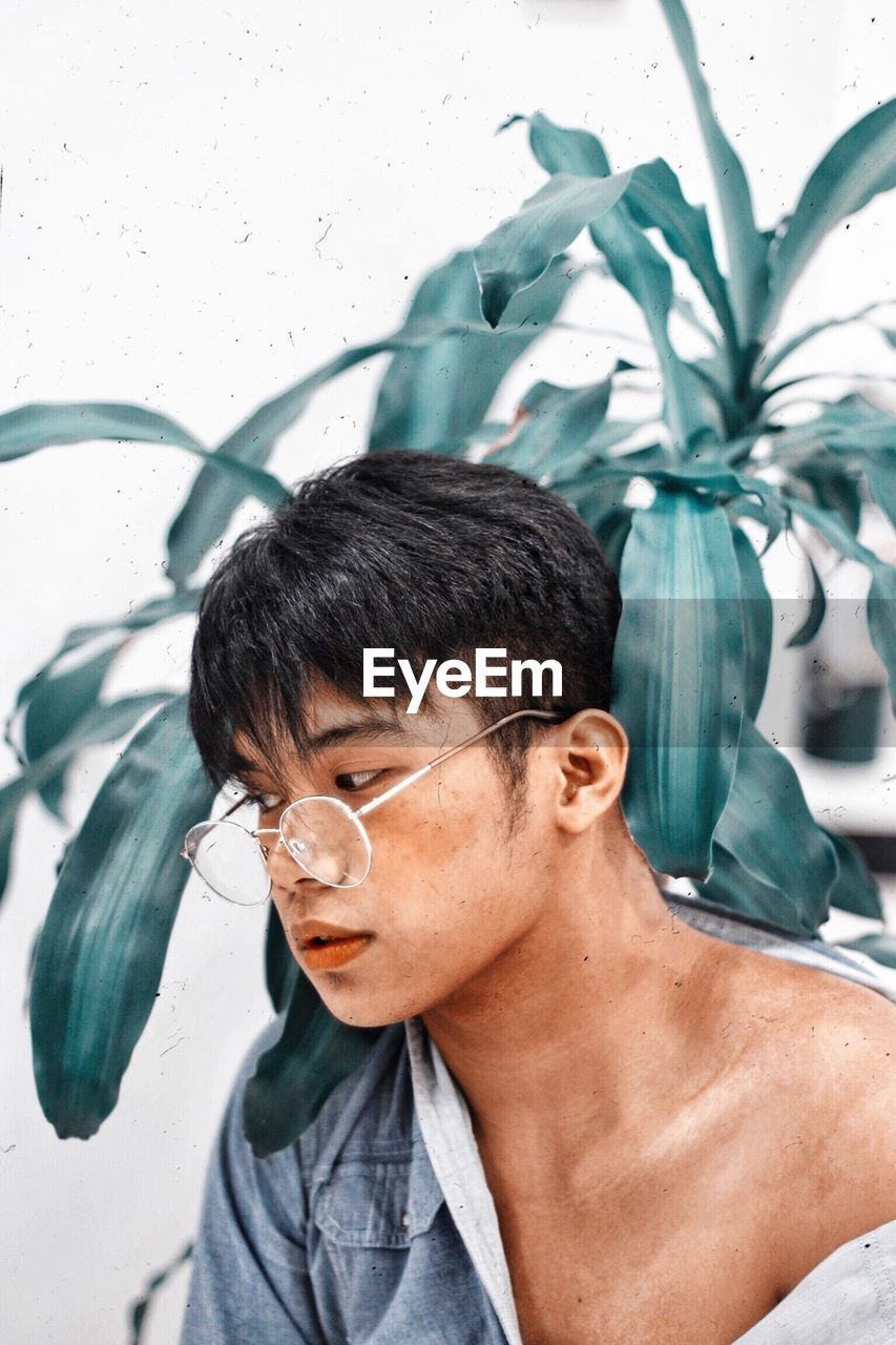 Close-up of young man wearing eyeglasses against plants