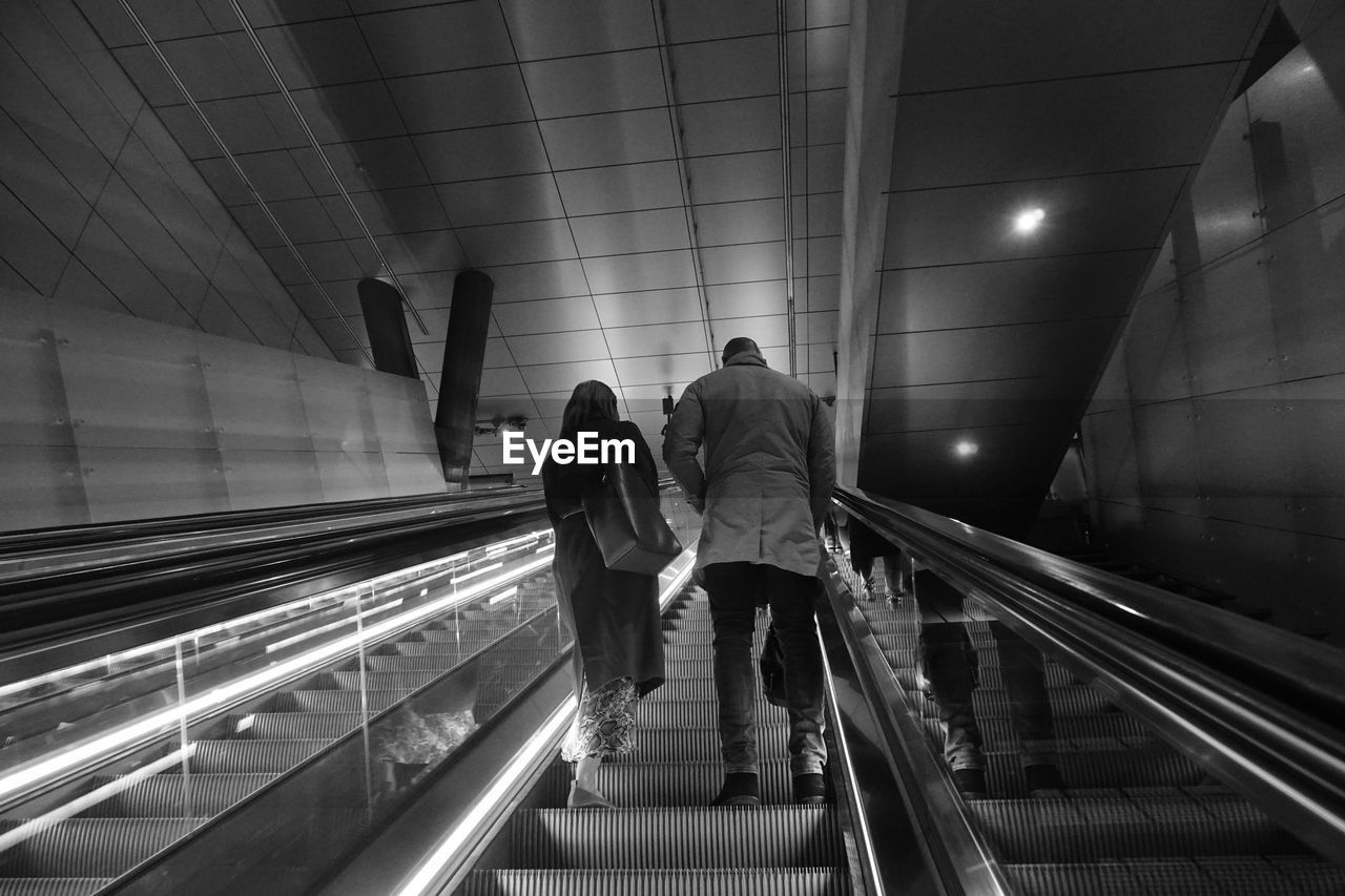 Rear view of people walking on escalator