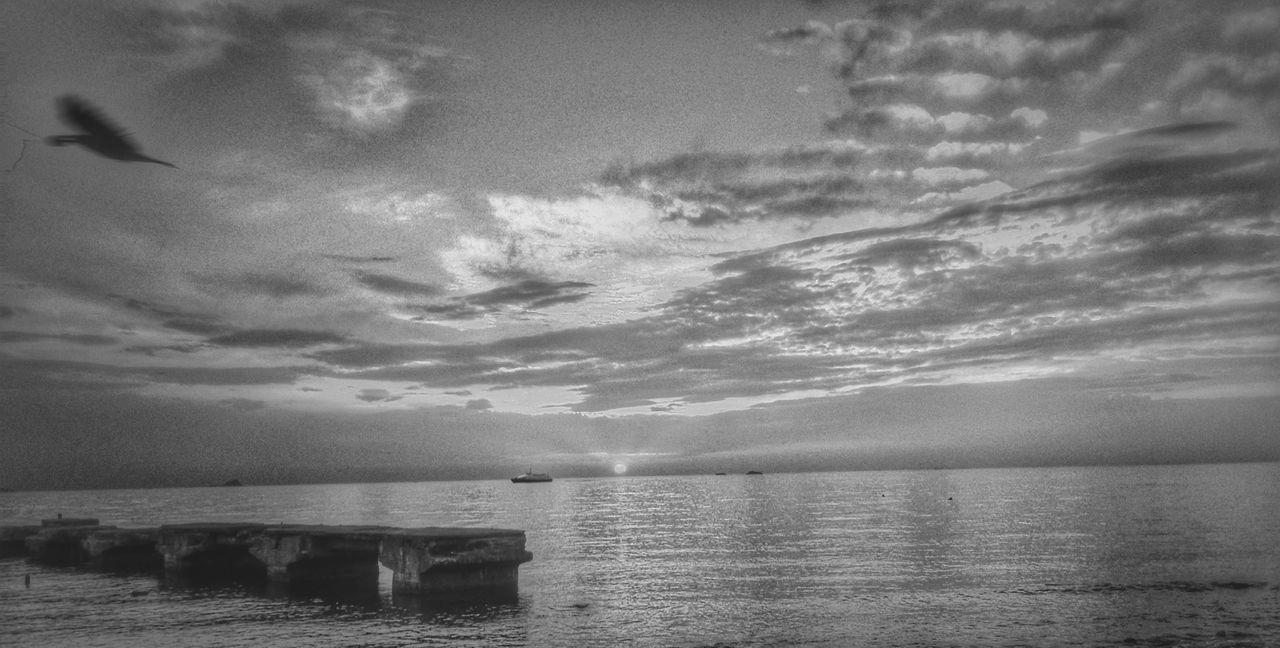 Scenic view of sea against cloudy sky during sunset