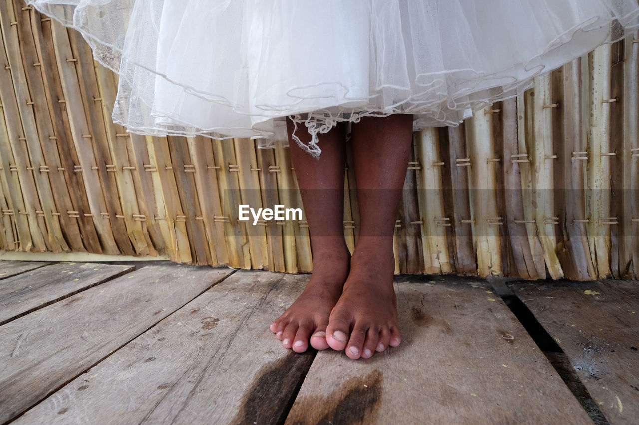 Low section of bride standing on wooden floor