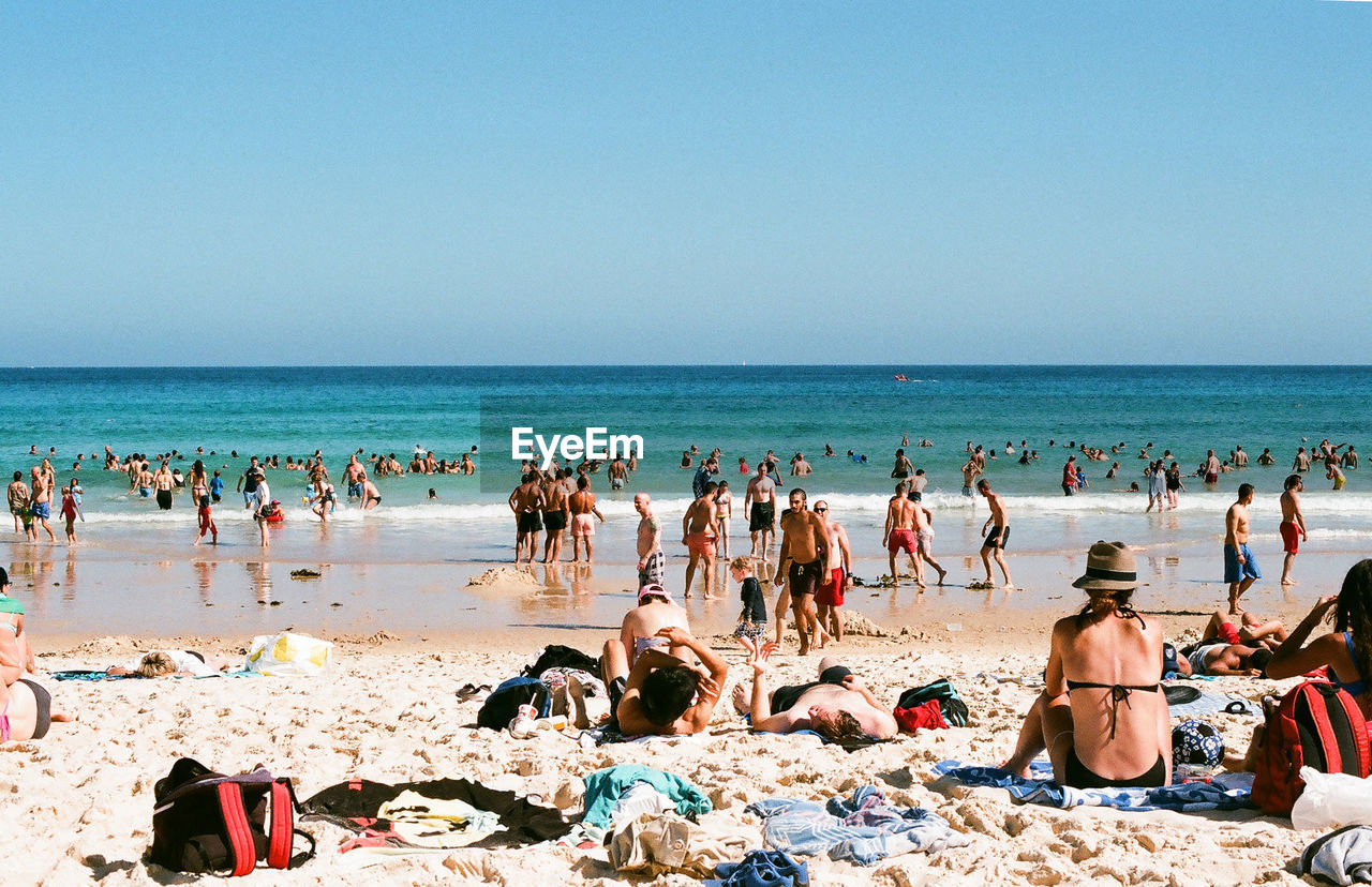 People enjoying at beach against clear sky