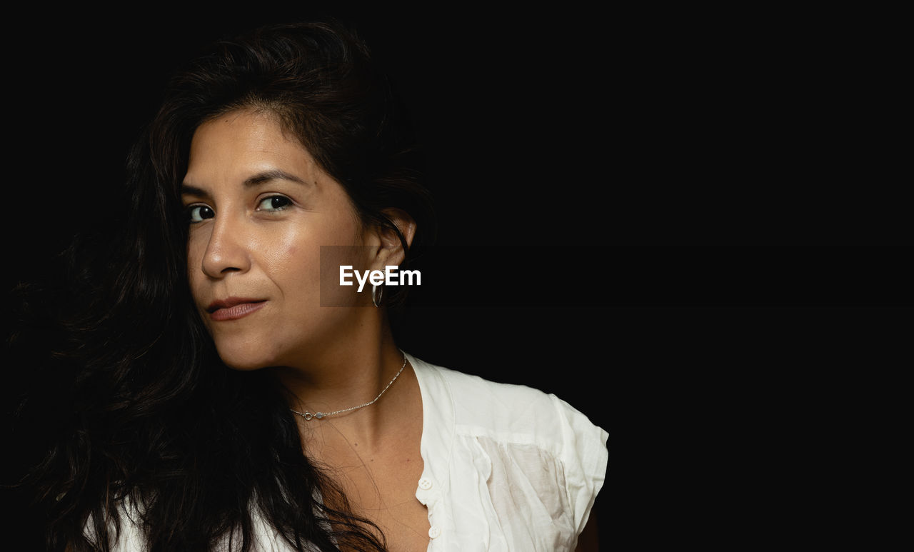 Latin secretary woman looking at camera with black background person