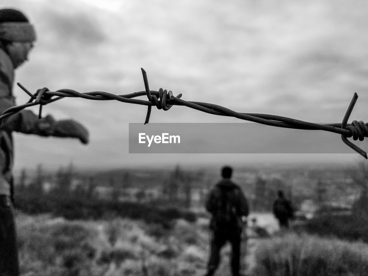 Close-up of barbed wire fence against sky