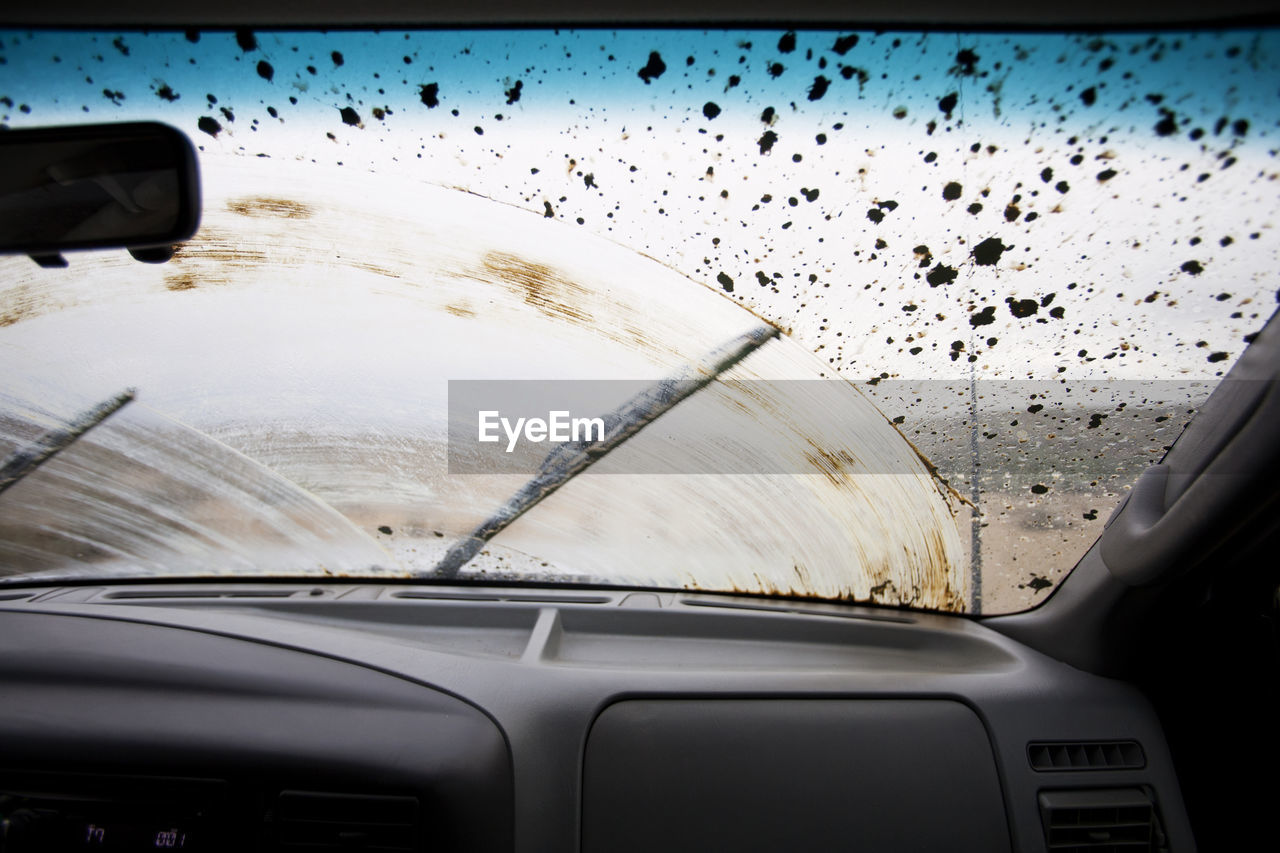 Wiper moving on dirty windshield seen through car