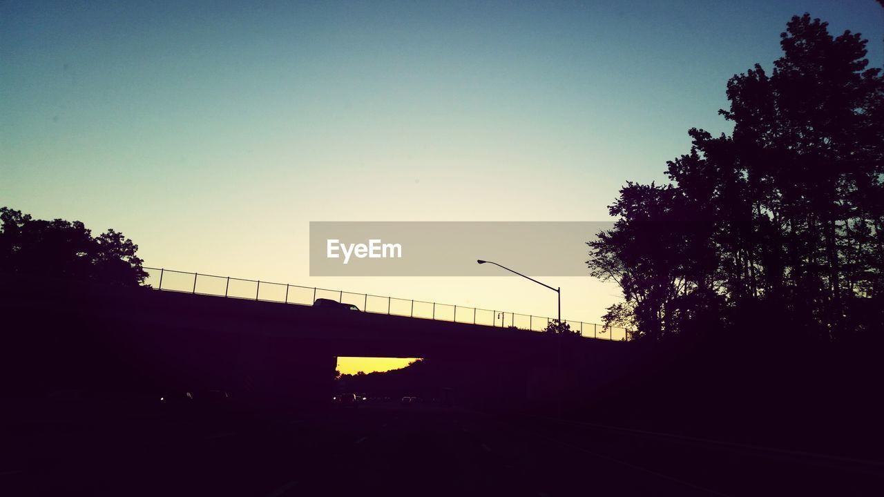 Low angle view of silhouette bridge against clear blue sky