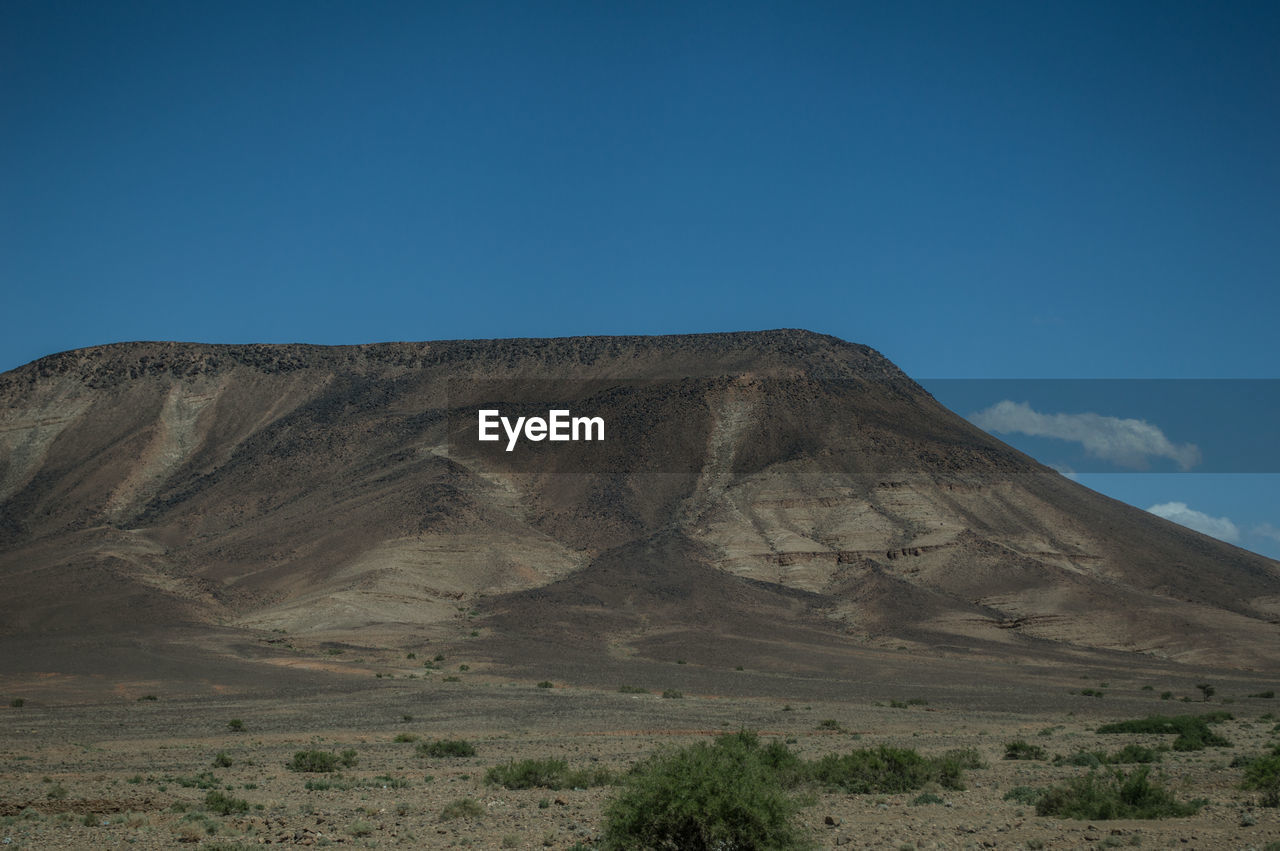 Scenic view of mountain against blue sky during sunny day