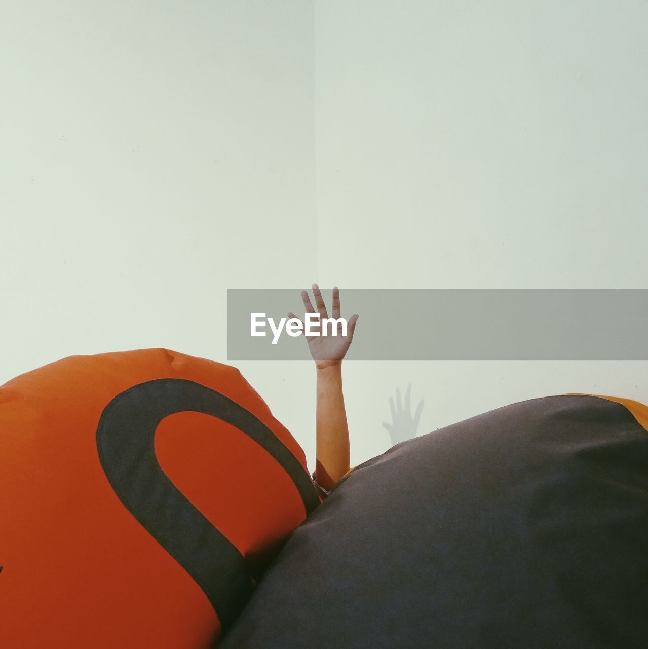 Cropped hand amidst bean bag against wall at home