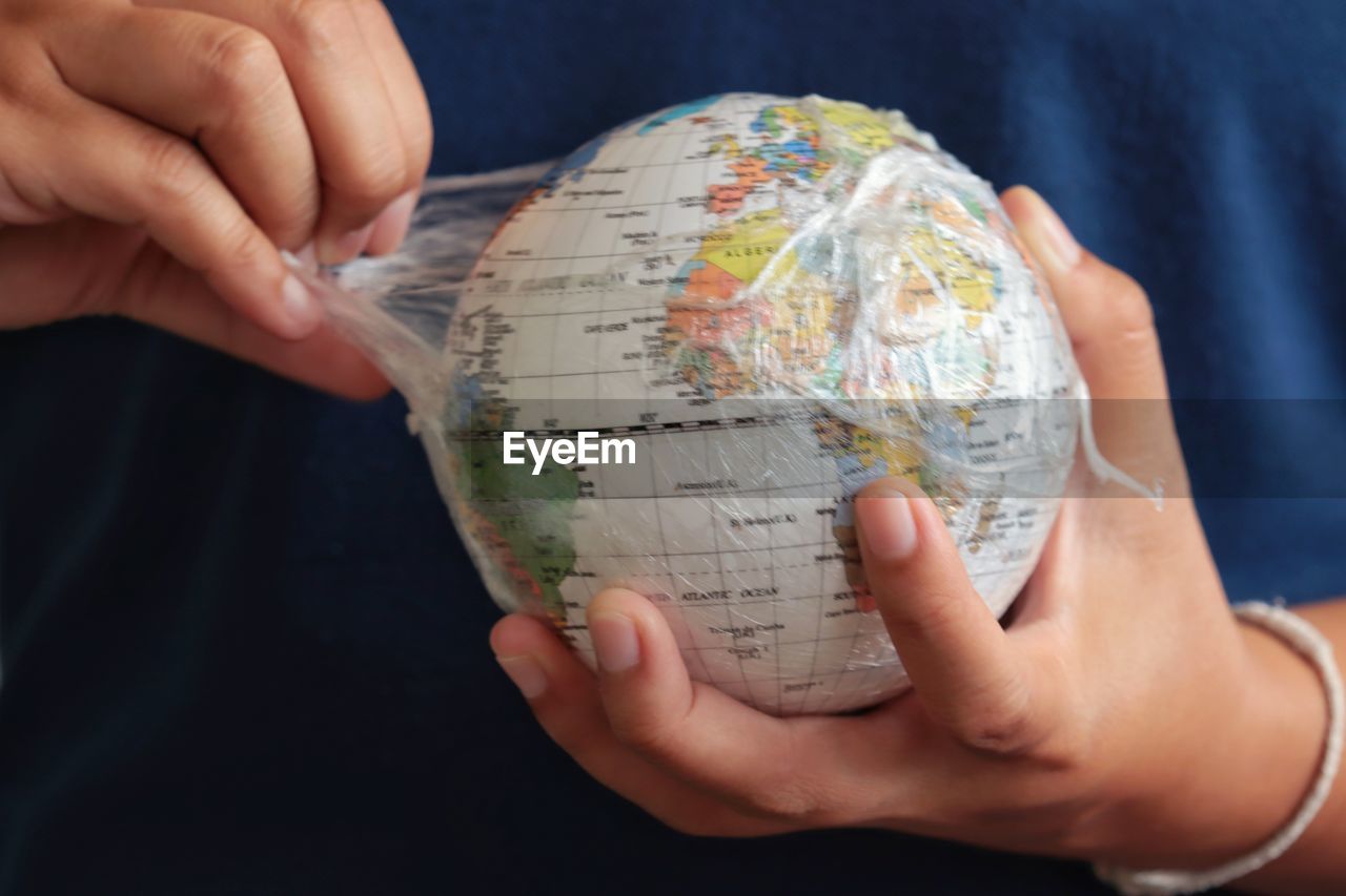 Midsection of man holding globe in plastic bag