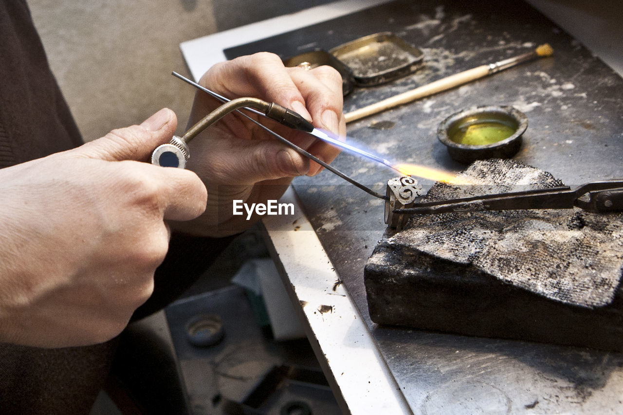 Cropped hands of person burning metal at workshop