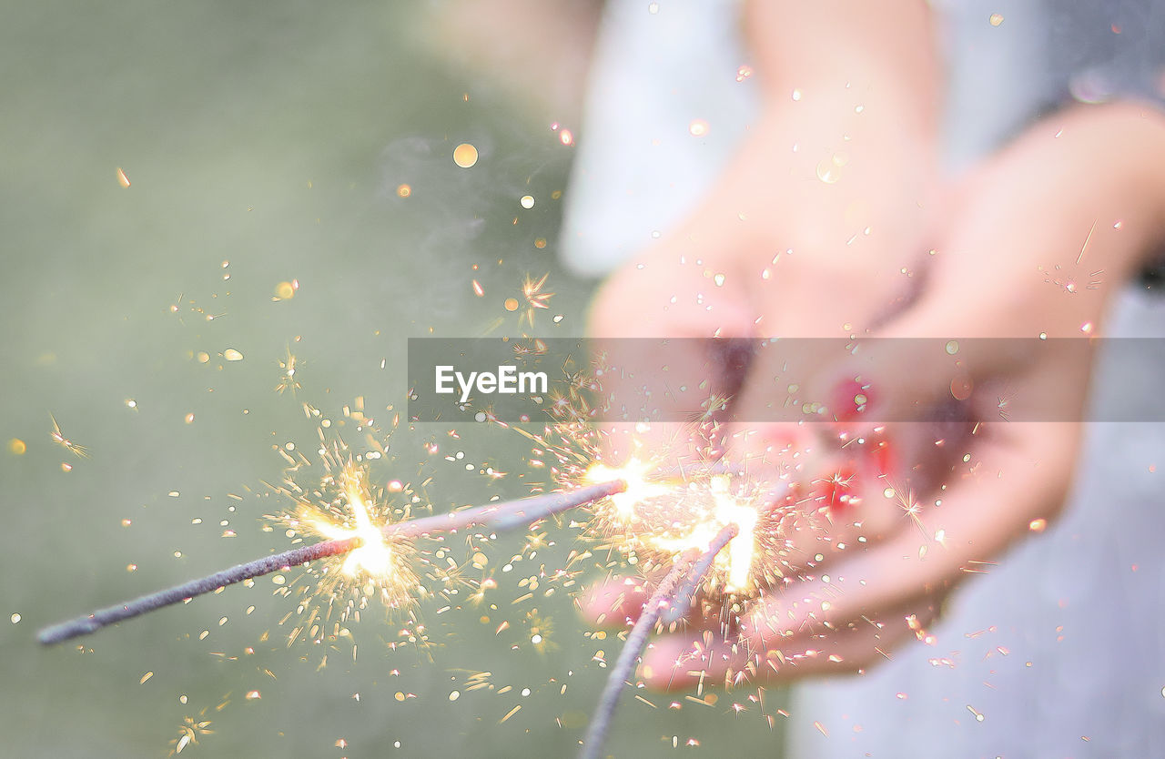 Midsection of woman holding sparklers outdoors