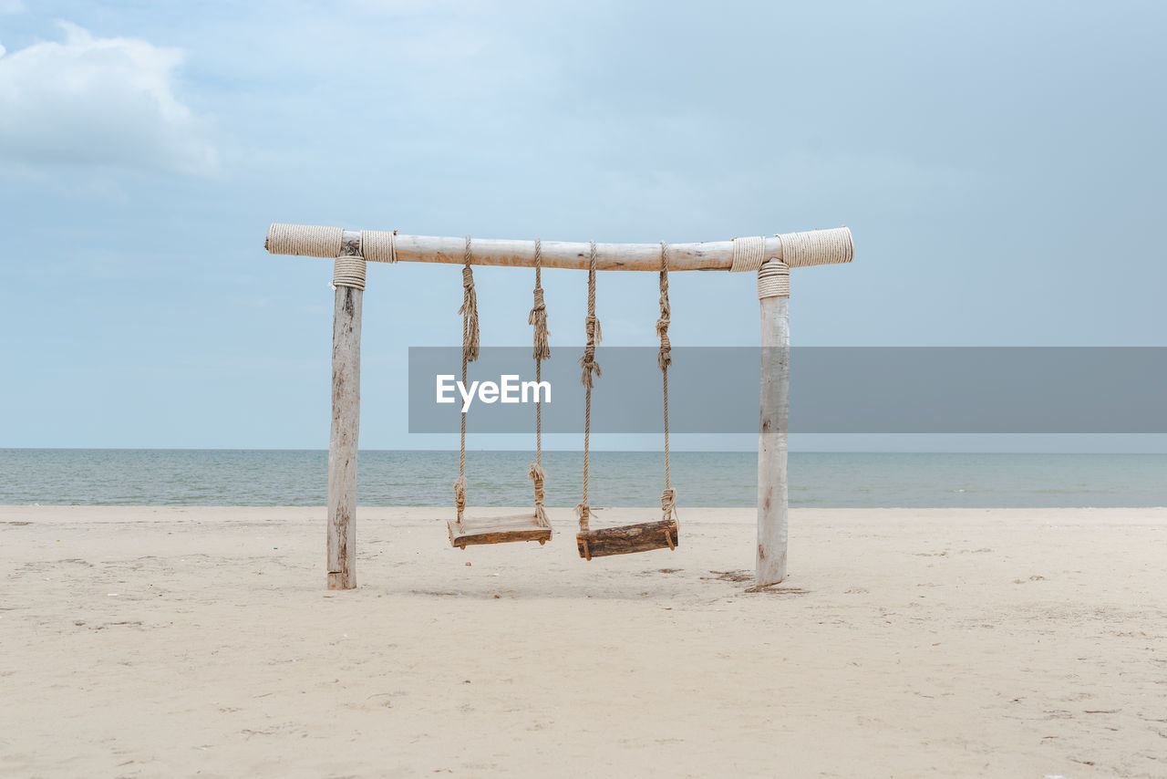 Wooden posts on beach against sky