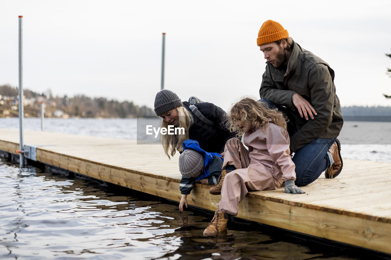 Man and woman with son and daughter on jetty at lake