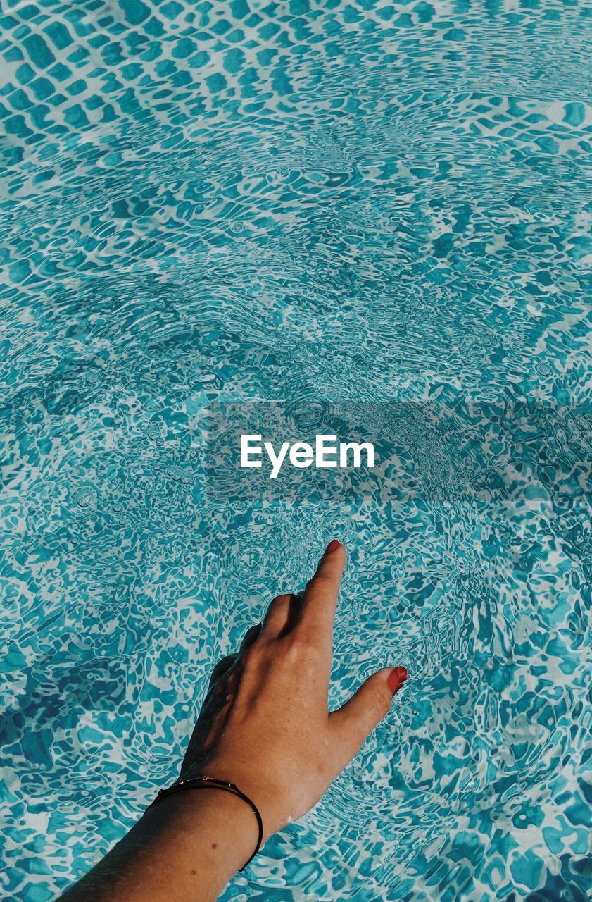 Close-up of woman touching water in swimming pool