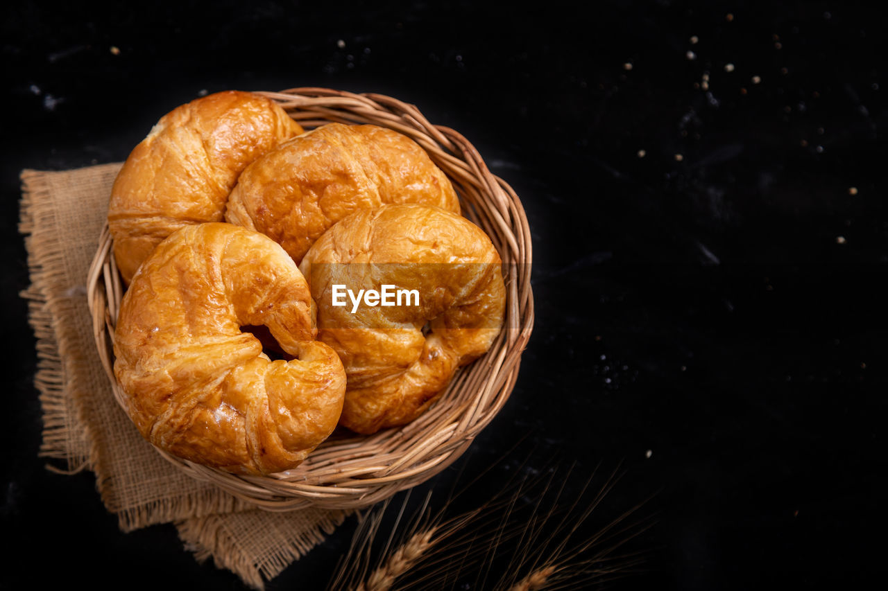 Top view croissant in the wicker basket on the black background.