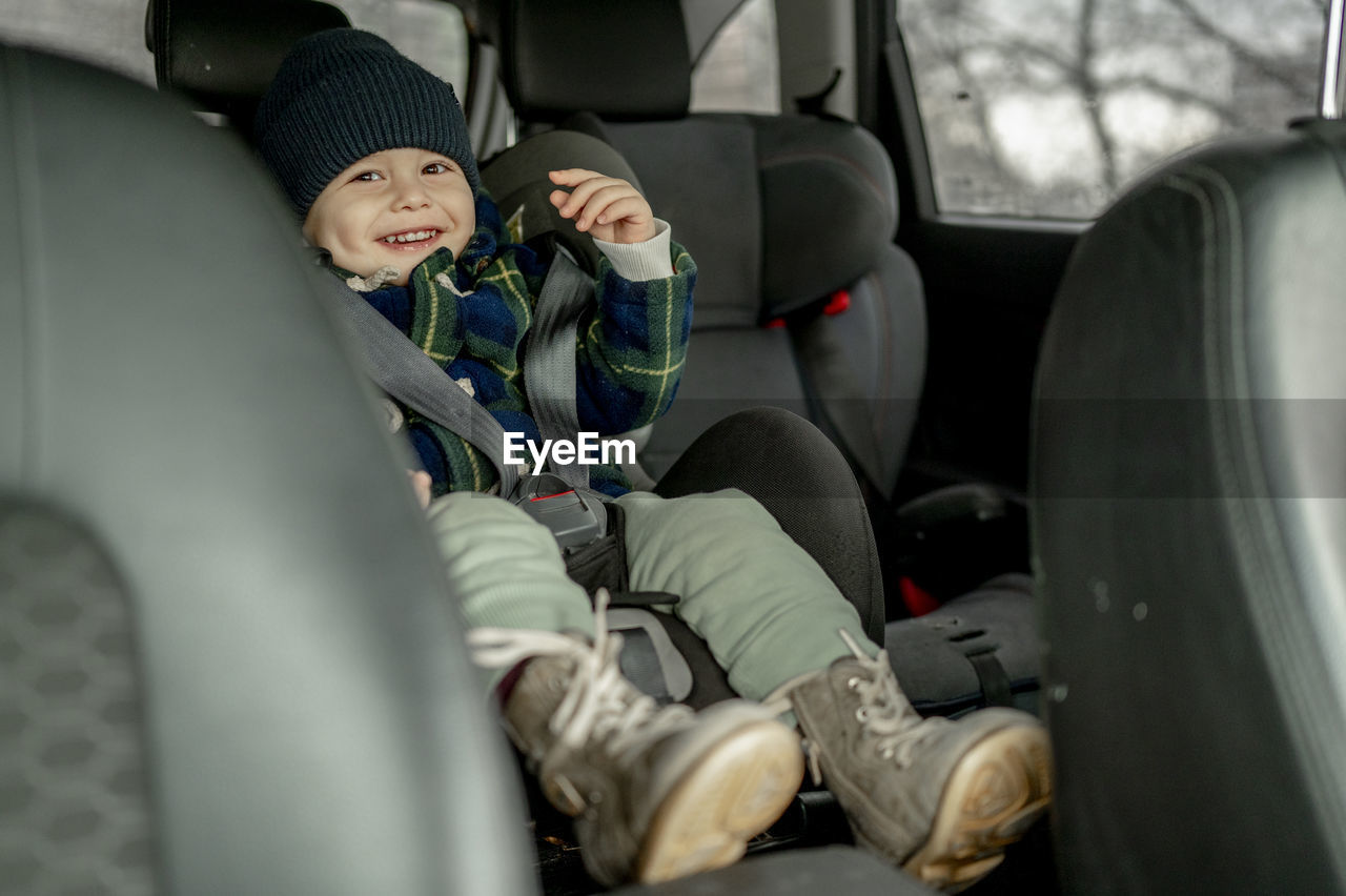 Happy cute boy in car safety seat