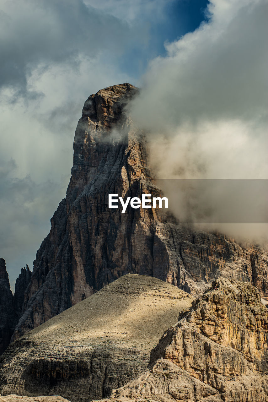 Low angle view of rock formations against cloudy sky