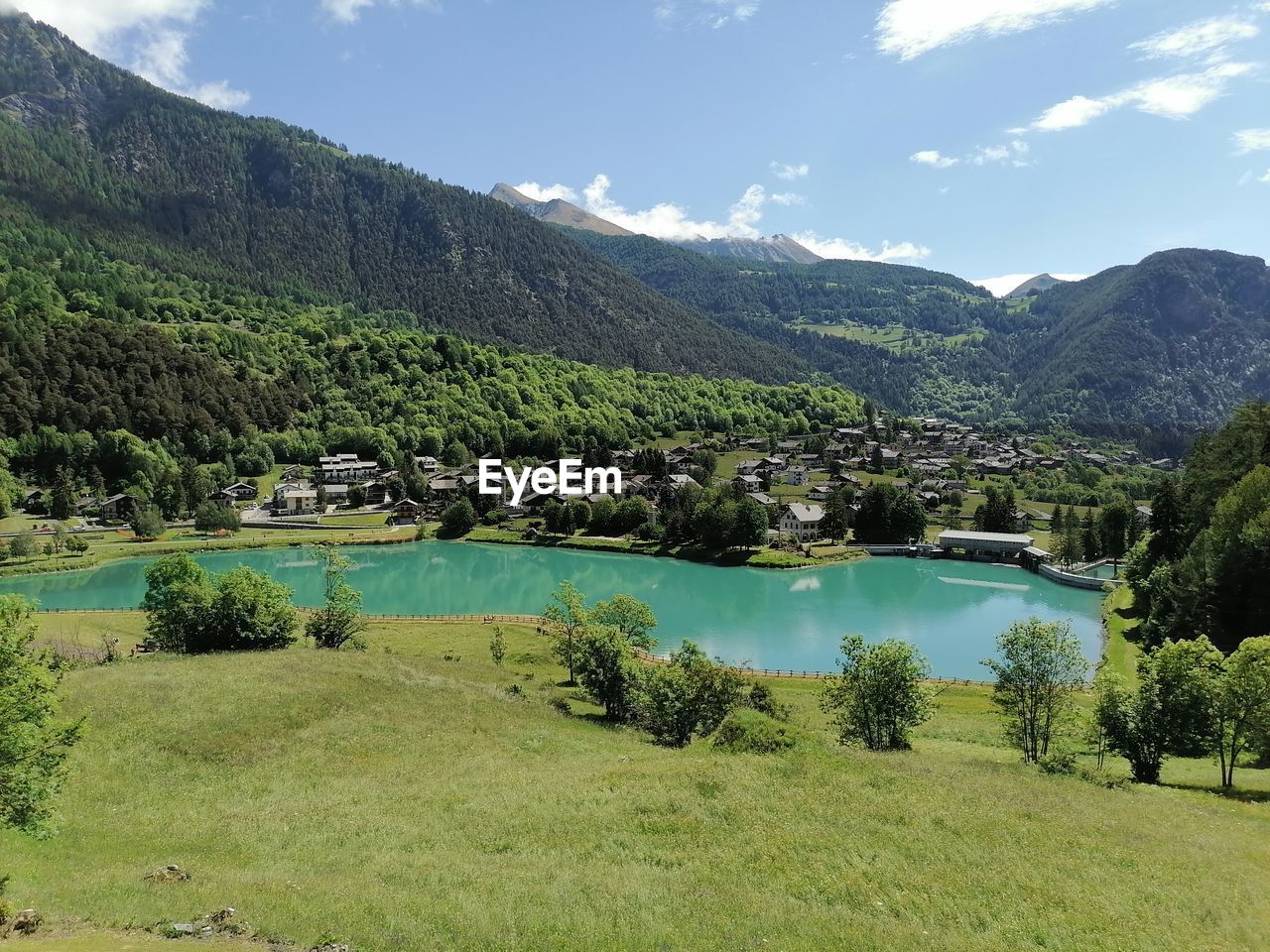 mountain, plant, scenics - nature, environment, landscape, tree, water, beauty in nature, nature, lake, sky, land, mountain range, tranquility, green, valley, grass, tranquil scene, no people, forest, pine tree, pinaceae, coniferous tree, reservoir, travel destinations, cloud, non-urban scene, pine woodland, travel, day, blue, outdoors, idyllic, highland, tourism, summer, field, plateau, architecture, rural scene, meadow, sunlight, activity, environmental conservation, wilderness, social issues, building