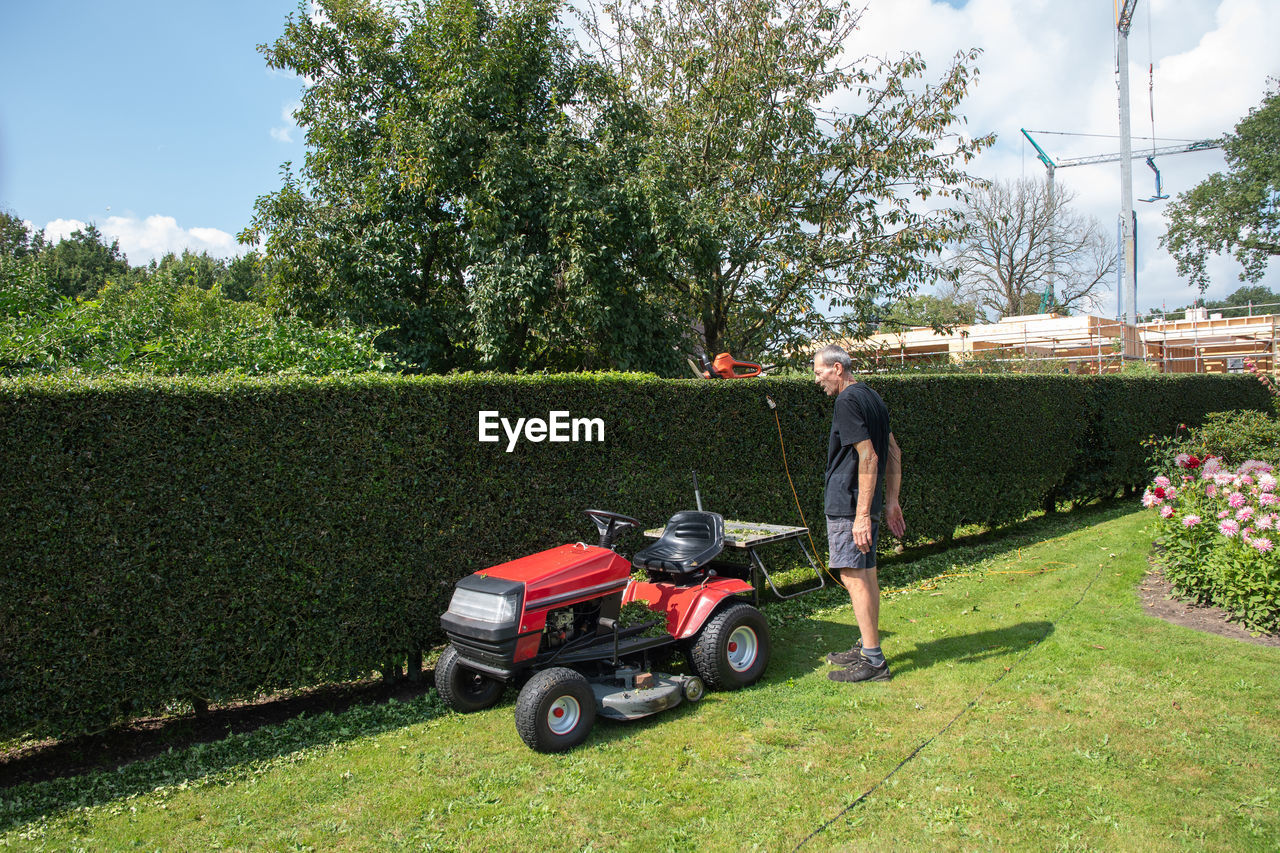 Male gardener using a lawn mowing tractor for cutting grass, gardening