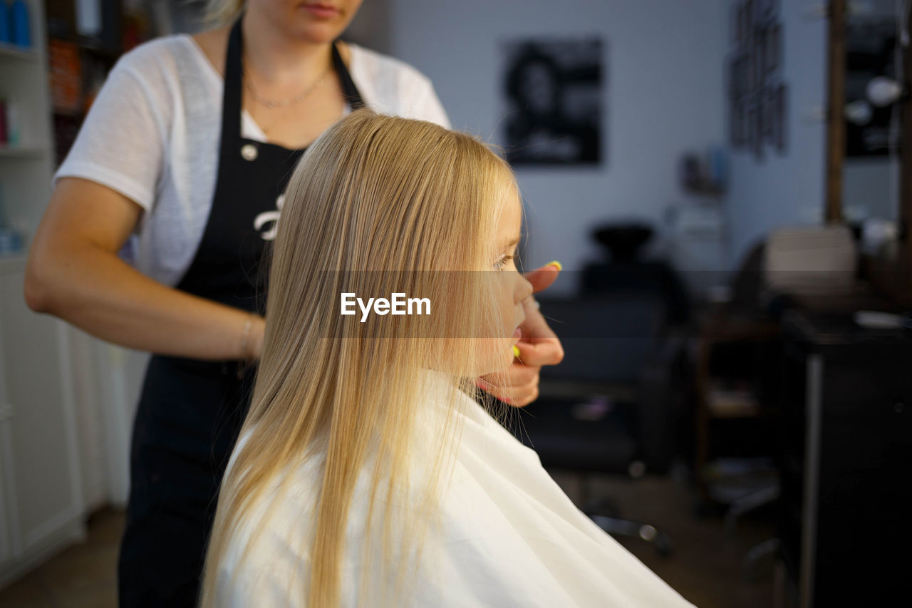 Hairdresser working on girl hair in salon