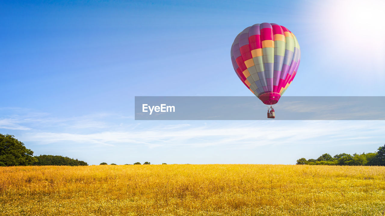 HOT AIR BALLOON FLYING OVER FIELD