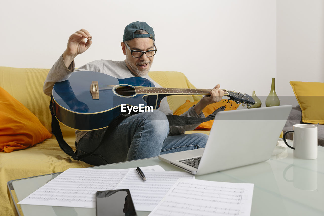 Musician playing the guitar online with his colleagues