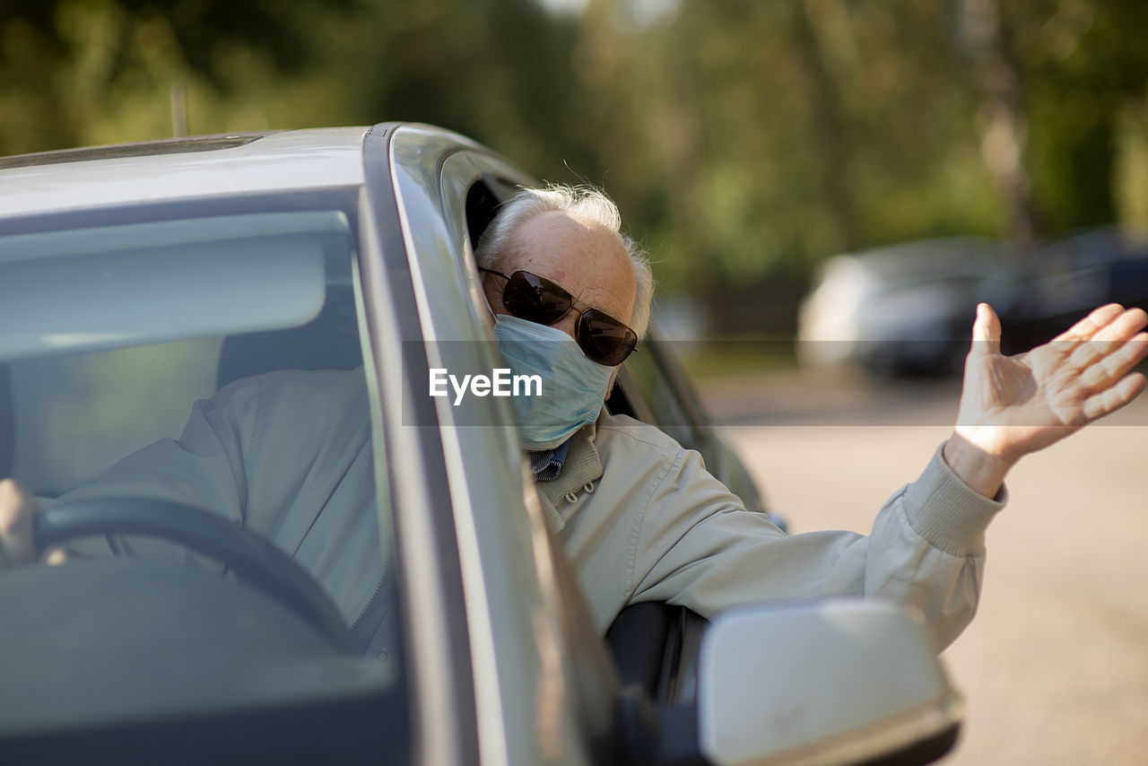 Senior man wearing anti virus mask are driving in a car during the covid-19 pandemic