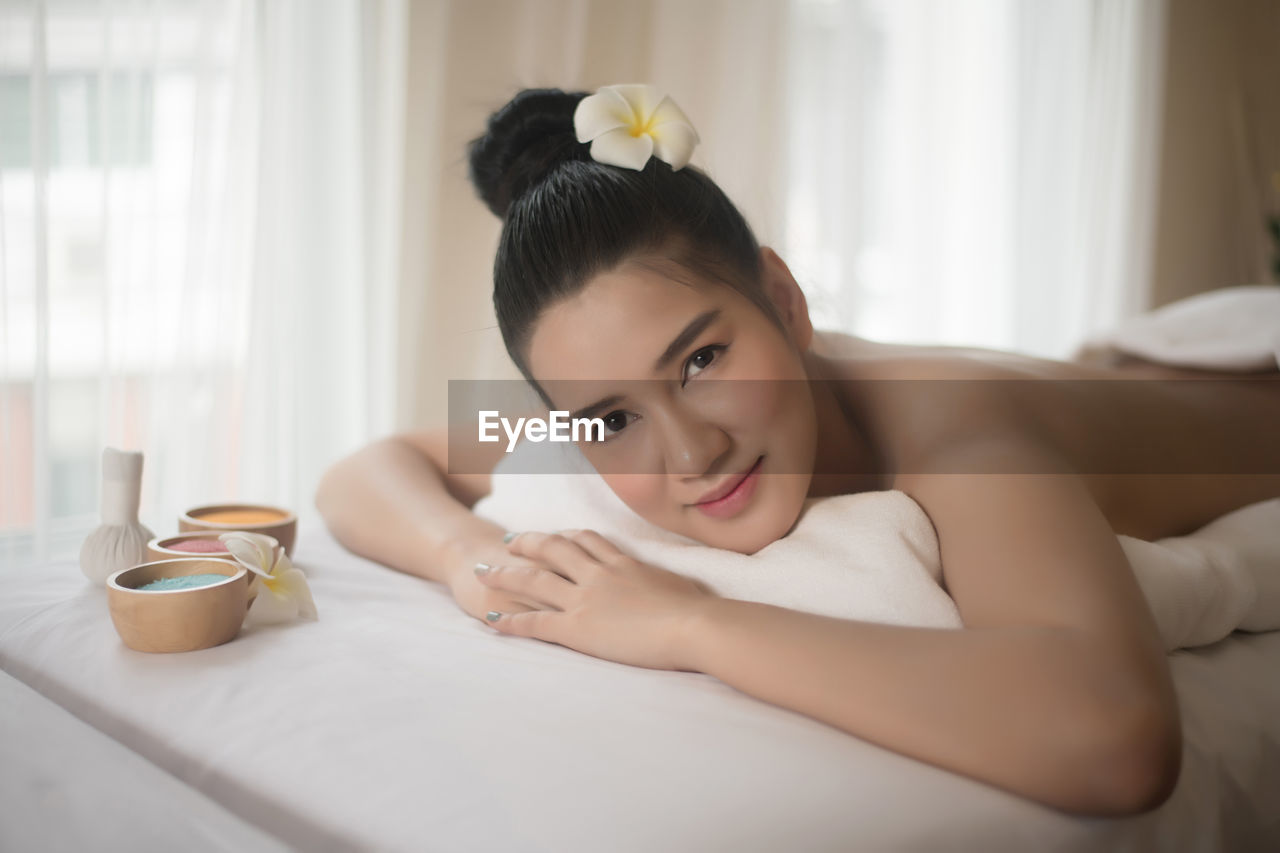 Portrait of smiling young woman lying on massage table in spa