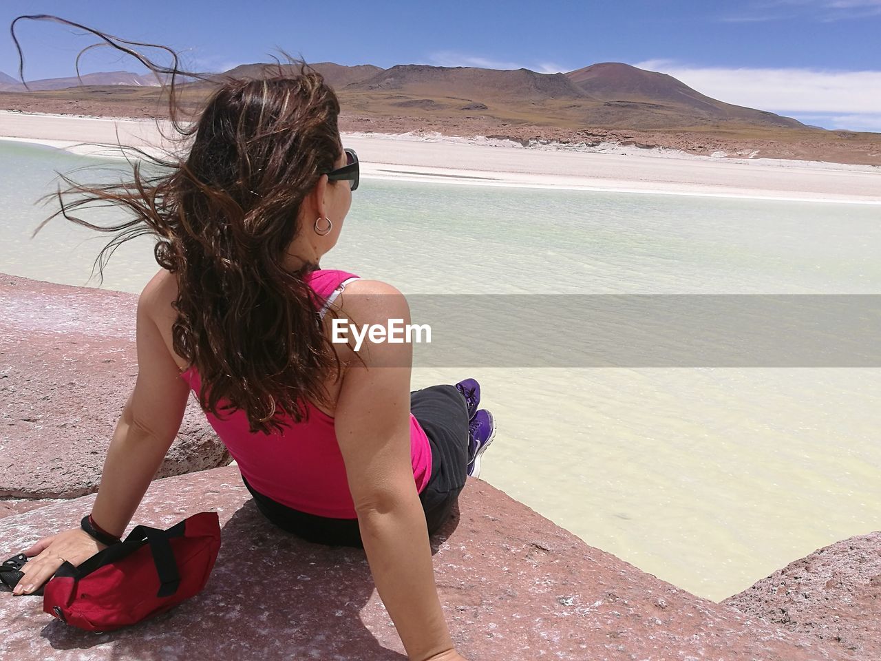 Rear view of woman sitting on rock against sea