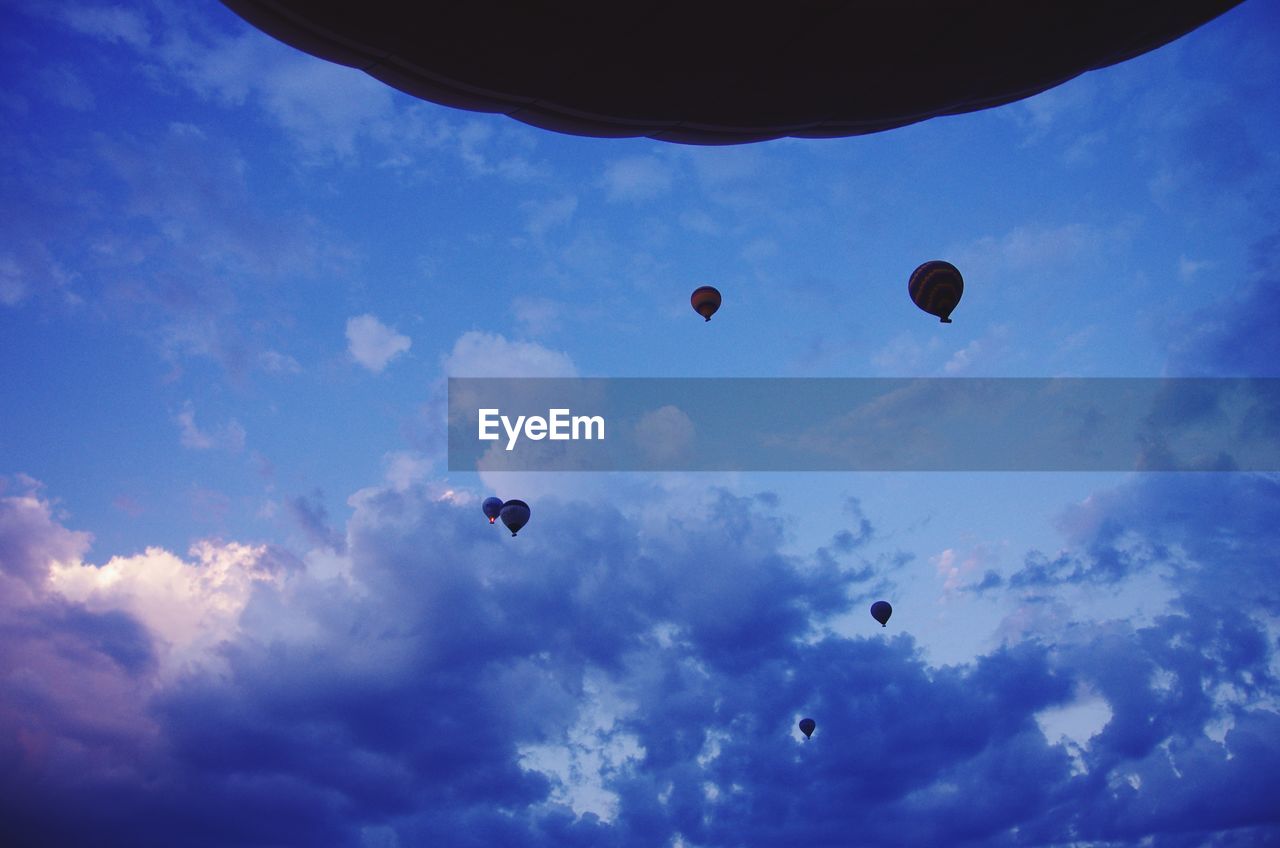 Low angle view of hot air balloons against cloudy sky